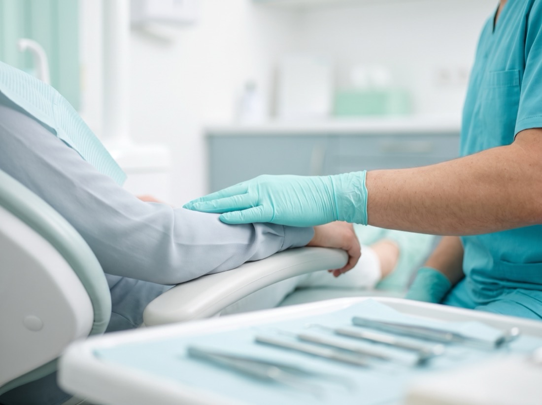 Mão da dentista acolhendo o paciente ao lado da cadeira