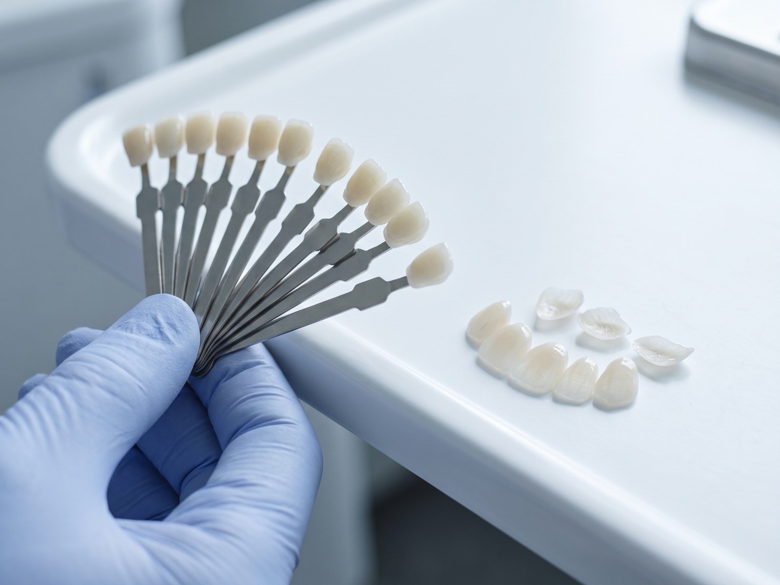 Escala de cores de porcelana e lâminas cerâmicas sobre bandeja clínica